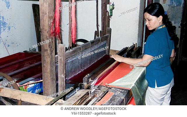 Woman operates silk loom tailor shop historic Hoi An Vietnam