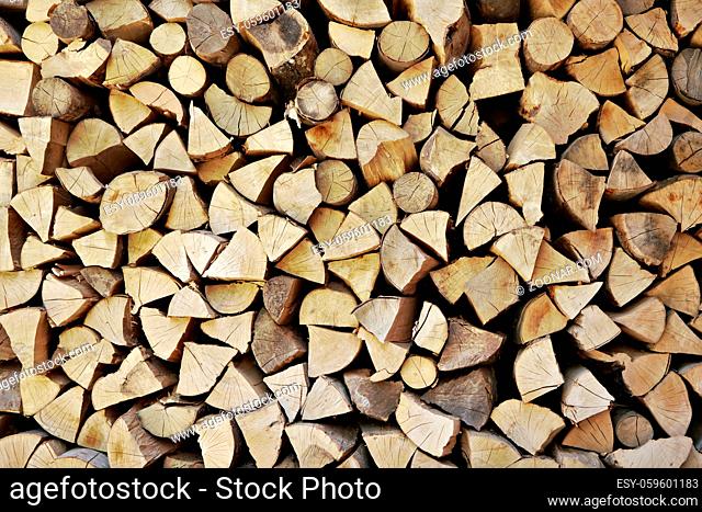 Wooden logs cut to pieces stacked as firewood near house
