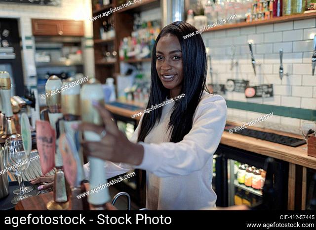 Portrait happy young female bartender behind bar