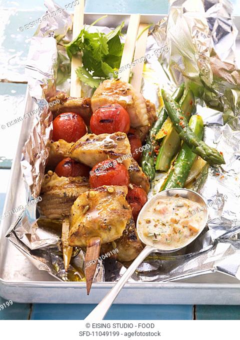 Grilled wels catfish and tomato kebabs with green asparagus and spicy yogurt dip