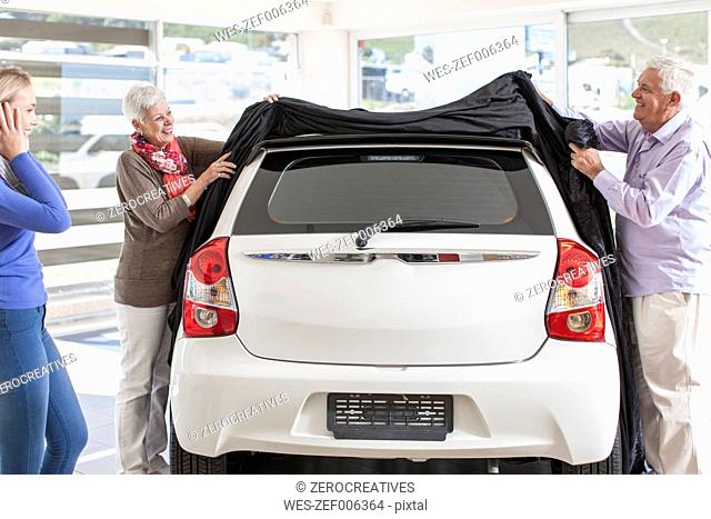 Father and mother unveiling new car as gift for the daughter
