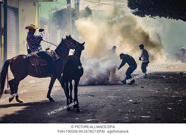 05 March 2019, Mexico, San Juan de la Vega: A man on a horse laughs as he picks up participants of the ""Festival of Explosive Hammers"" with his mobile phone
