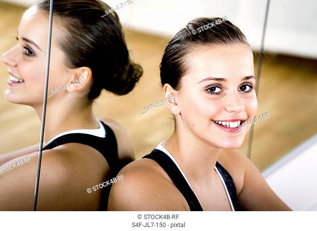 Sporty teenage girl leaning against mirror wall, portrait