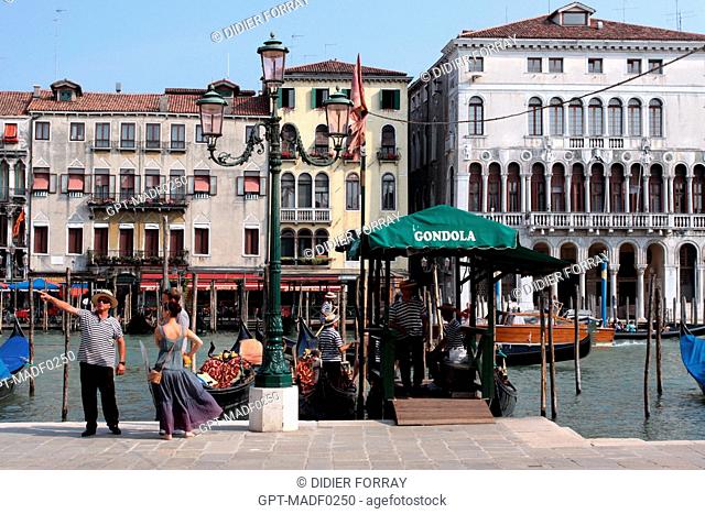 GONDOLIERS INVITING TOURISTS FOR A SIGHTSEEING RIDE IN A GONDOLA ON THE GRAND CANAL, VENICE, VENETIA, ITALY