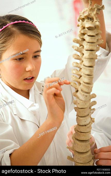 Curious junior high school girl examining spine model in science class