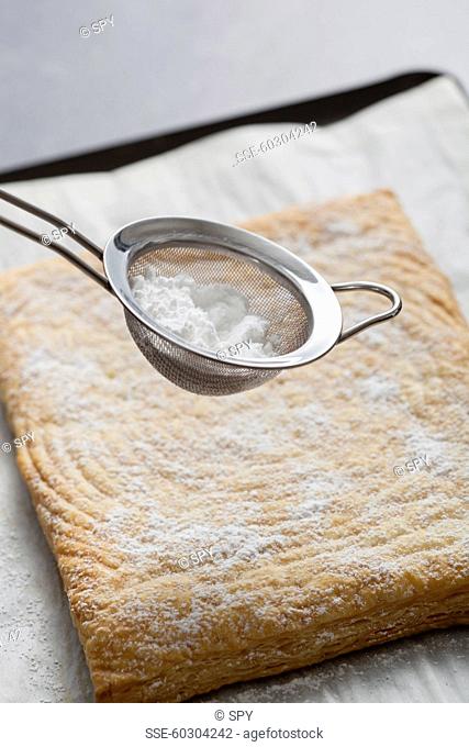 Sprinkling the icing sugar onto the flaky pastry