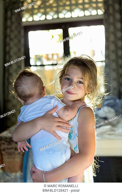 Caucasian girl carrying baby boy in bedroom