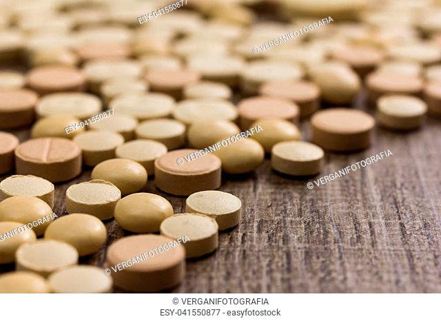 Heap of assorted beige capsules on wooden table
