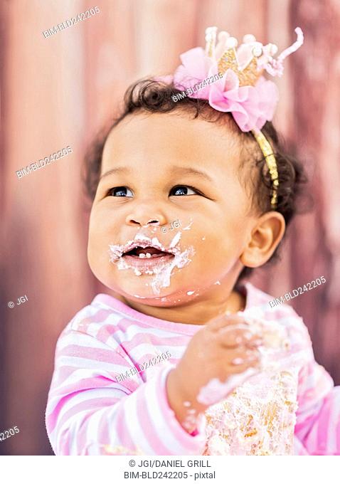 Messy Mixed Race baby eating birthday cake