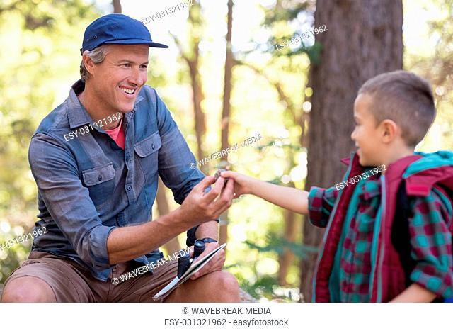 Boy giving pine cone to father in forest