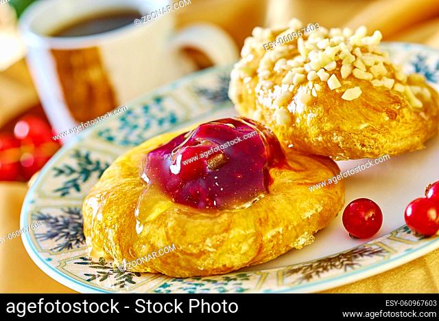 cheesecake with jam on a plate against the background of the cup with a sprig of red currants Food being prepared and cooked in a contemporary kitchen