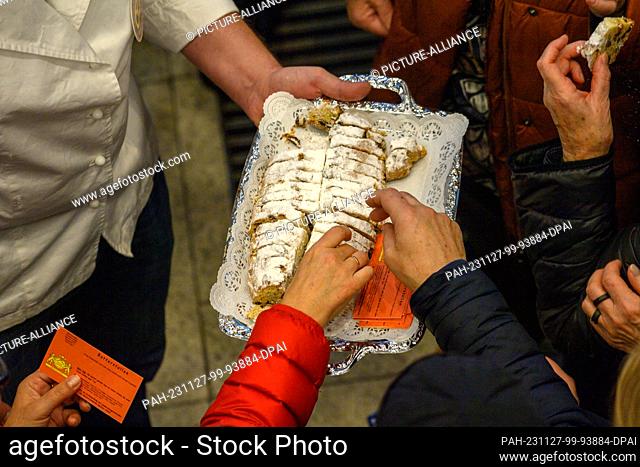 27 November 2023, Saxony-Anhalt, Magdeburg: Spectators take Christmas stollen from a tray to taste for themselves at the German Bread Institute's stollen test