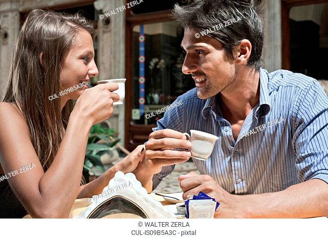 Young couple sitting outside cafe, drinking coffee, Turin, Piedmont, Italy