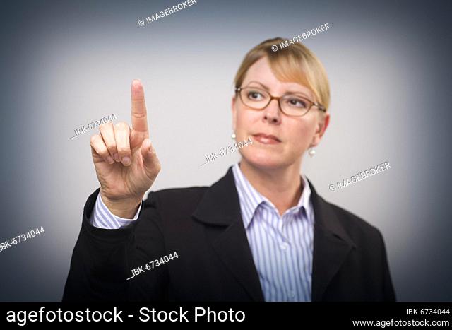 Businesswoman reaching out with finger, ready for your own buttons or touch screen, focus is on her finger