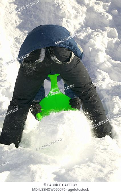 Young boy digging snow