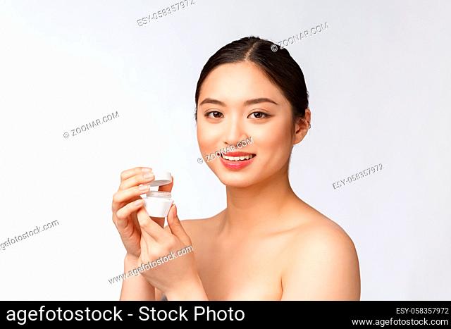 Beautiful young woman on white isolated background holding cosmetic face cream, asian