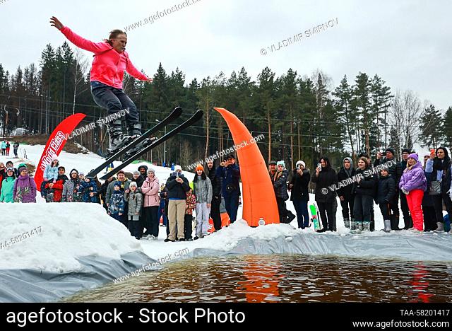 RUSSIA, IVANOVO REGION - APRIL 2, 2023: A dressed-up skier performs a jump over water during the 2023 edition of Easy-Freezy Festival at Milovka ski resort in...