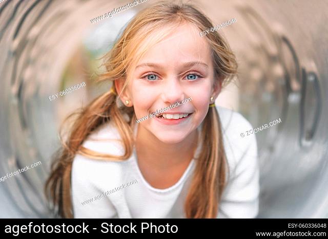 Pretty, little girl, having fun, lying on pipe on children playground