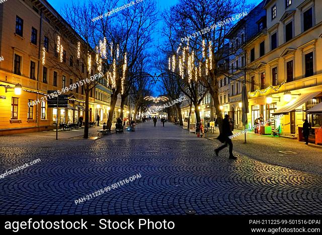 20 December 2021, Thuringia, Weimar: A man walks along Schillerstraße in the late afternoon. Due to the Corona pandemic, there is no Christmas market this year...