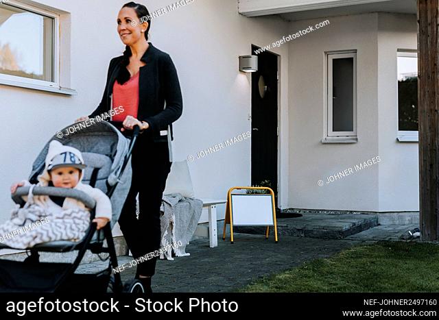 Woman with pram in front of house