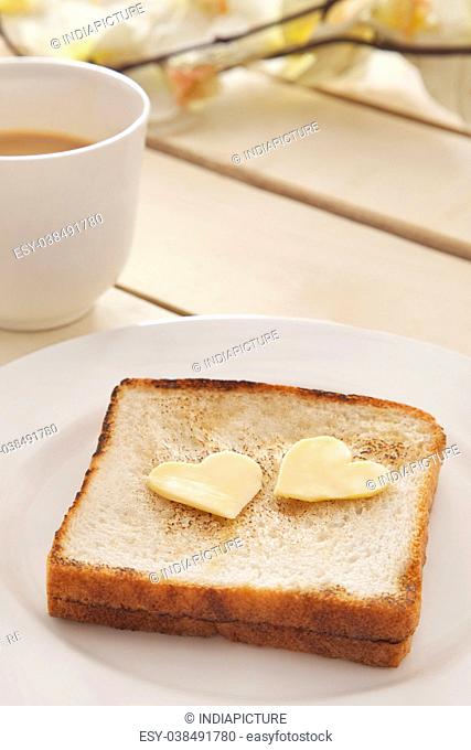 Toasted bread with heart shaped butter and cup of tea