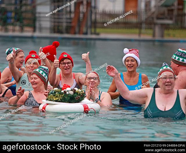 10 December 2023, Saxony-Anhalt, Osterwieck: Participants in the Advent swim stand in the water at 6 degrees Celsius in the Osterwieck outdoor pool and give the...
