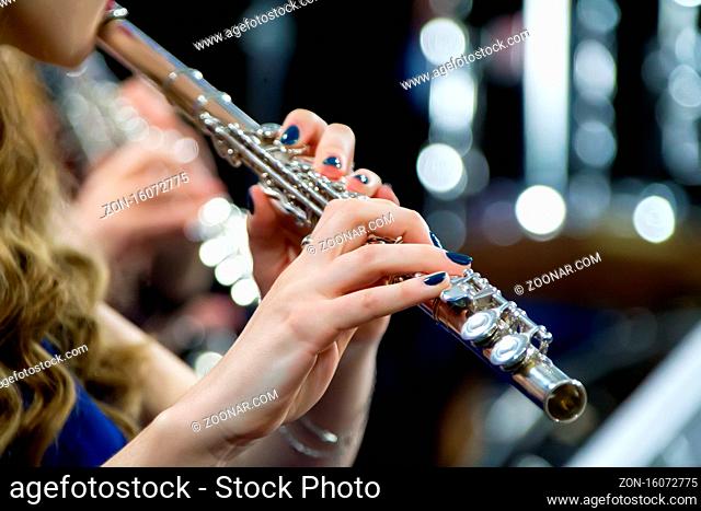 Hands holding a flute. Girl musician plays the flute
