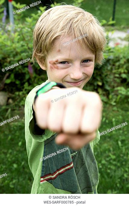 Portrait of boy with graze in his face showing fist