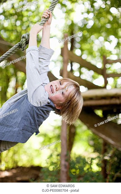 Portrait of boy hanging from rope swing