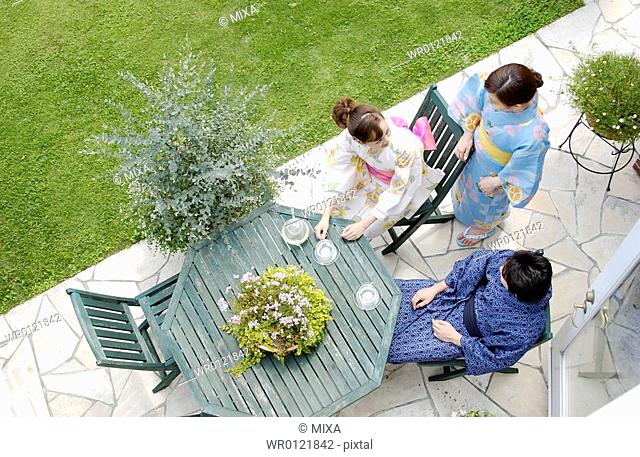 Three people in kimono sitting at outdoor table