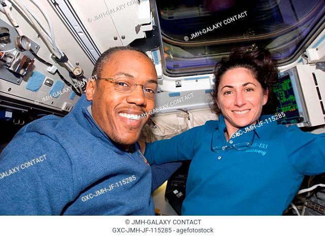 Astronauts Alvin Drew and Nicole Stott, both STS-133 mission specialists, take a break from flight day 2 duties on Discovery's aft flight deck as the shuttle...