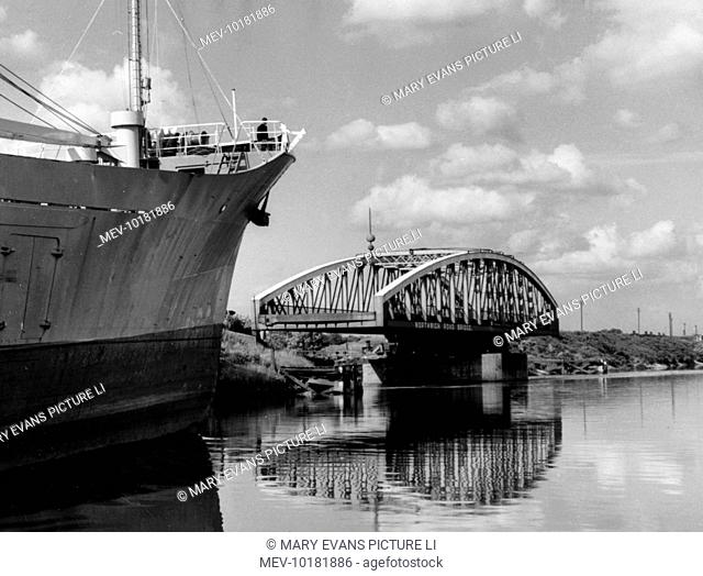 A scene on the Manchester Ship Canal at Warrington, Cheshire, England, showing the Northwich Road Swing Bridge, opened to allow a large vessel to pass along the...