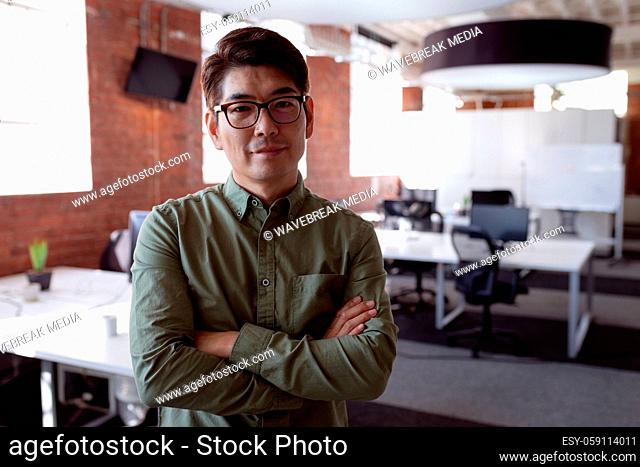 Portrait of serious asian businessman standing in office with arms crossed looking to camera