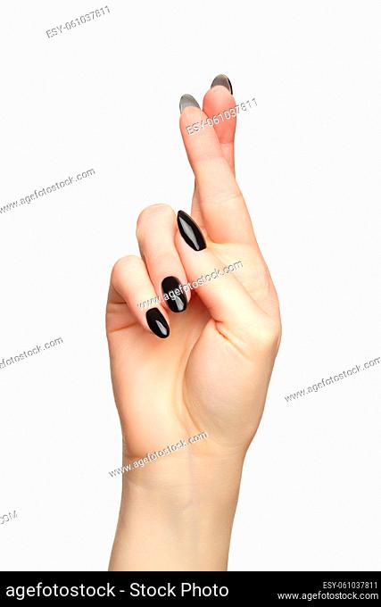 Female hand with black nails manicure with fingers crossed. Isolated on white background