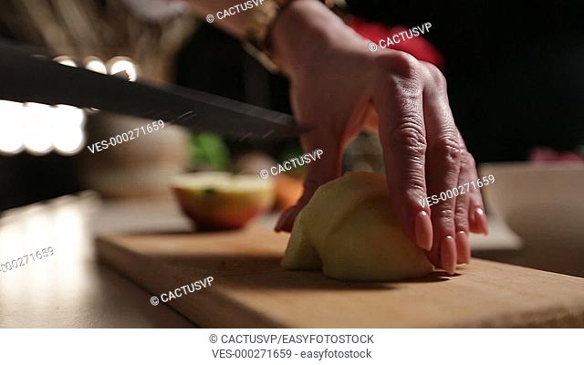 Female hand slicing peeled apple on cutting board
