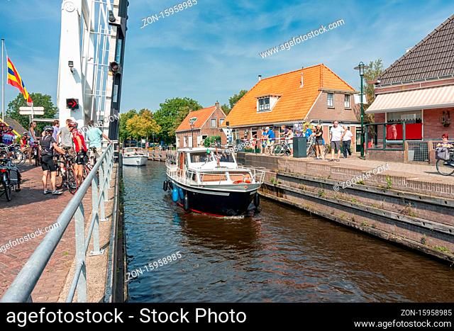 Ossenzijl, The Netherlands- September 03, 2011: Pedestrians and bikers waiting for opened bridge while yachts passing in the canal