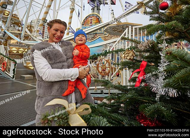 03 November 2023, Berlin: Dajana, operator of the Ferris wheel, holds her son Travis, born on 27.12.2022, in her arms at the ""Winterzauber"" Christmas market...