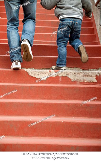 young father and his little son climbing together the red stairs