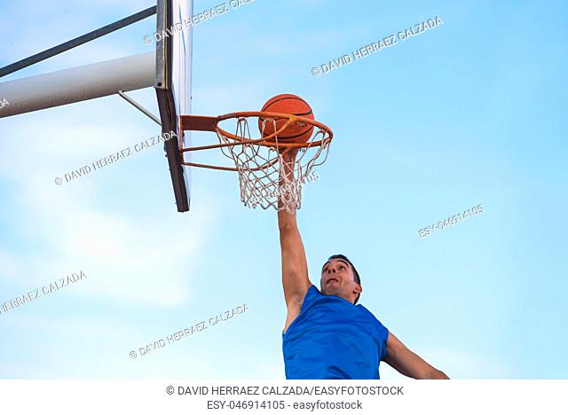 Street basketball athlete performing slam dunk on the court