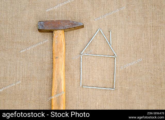 rusty hammer and shape of house made of nail, building new home concept