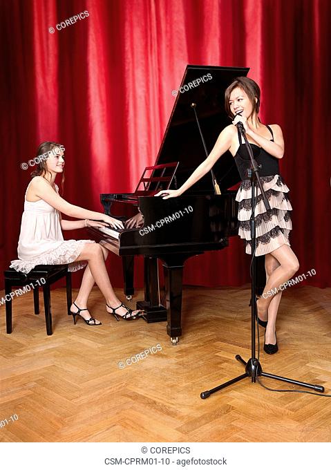 Duet with a young pianist behind a grand piano, looking at a beautiful lead singer
