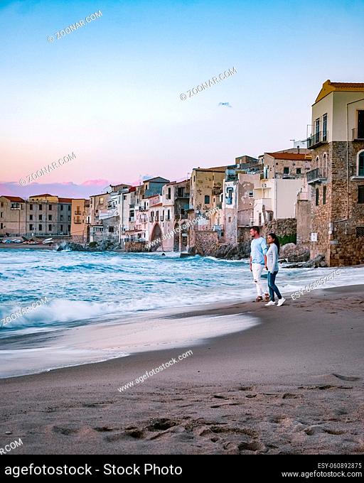 couple on vacation Sicily visiting the old town of Cefalu, sunset at the beach of Cefalu Sicily, old town of Cefalu Sicilia panoramic view at the colorful...