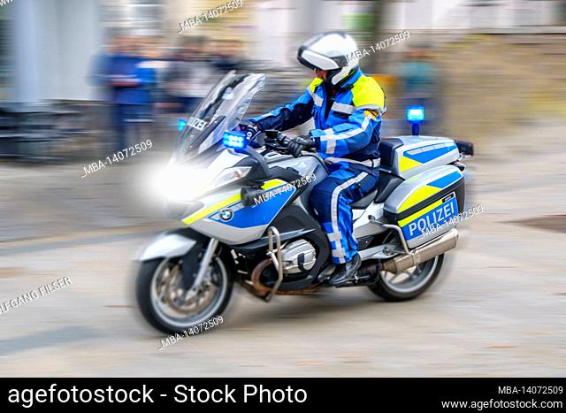 a police motorcycle drives through the city of augsburg at high speed and with blue lights