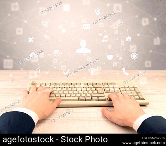 First person view of hand typing with social media concept icons around