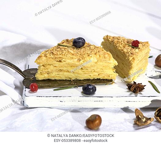 two baked cakes Napoleon with cream on a white wooden board, close up