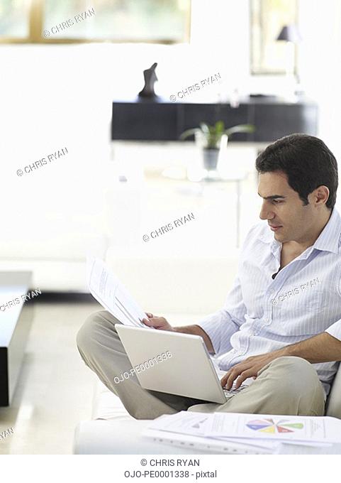 Man working on his laptop while relaxing at home