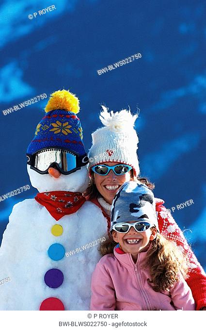 girls wearing sun glasses, standing beside snow man, France, Savoie