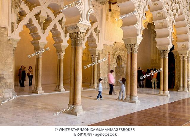 Tourists beneath the ornate stone carved arched passageway of the Santa Isabel Patio, Palacio de Aljaferia palace, Moorish architecture, Zaragoza, Saragossa