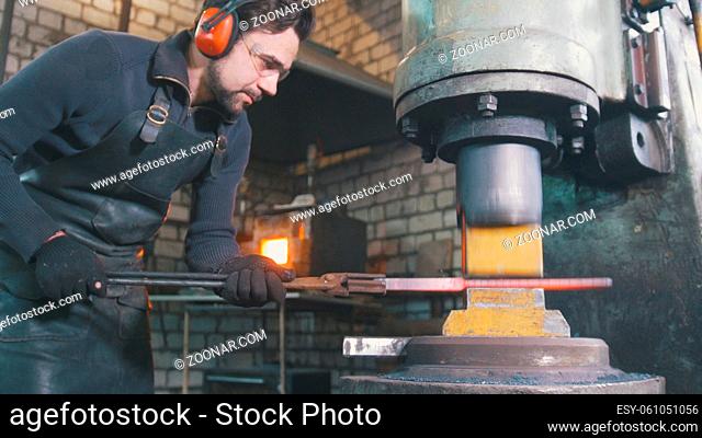 Blacksmith forging red hot iron on anvil - automatic hammering, telephoto