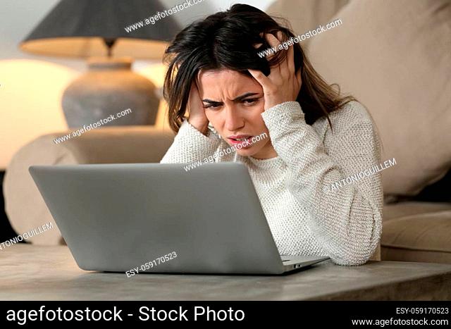 Desperate woman checking bad news on laptop in the living room at home